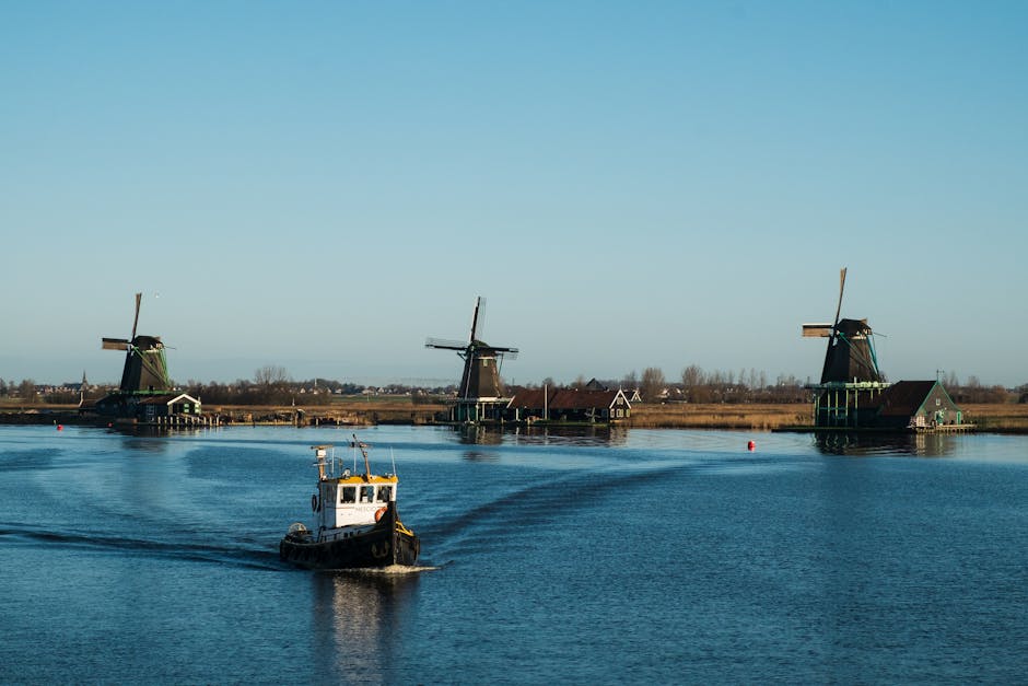 Traditional windmills and a boat on a calm waterway at Zaanse Schans in the Netherlands.
