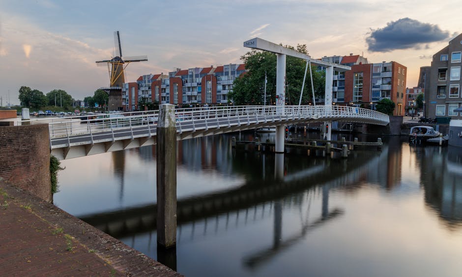 Tranquil sunset view of a drawbridge and windmill by Rotterdam canal.